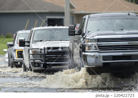 Flooded american street with moving vehicles surrounded with water in Florida residential area. Consequences of hurricane natural disaster Flooded american street with moving vehicles surrounded with water in Florida residential area. Consequences of hurricane natural disaster 120422725