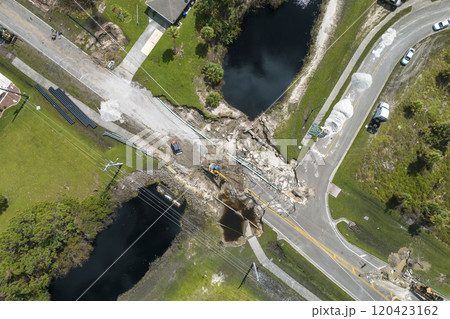 Destroyed bridge after hurricane flooding in Florida. Construction equipment at roadwork site. Reconstruction of damaged road after flood water washed away asphalt Destroyed bridge after hurricane flooding in Florida. Construction equipment at roadwork site. Reconstruction of damaged road after flood water washed away asphalt 120423162
