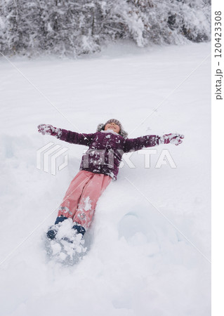 Little girl covered in snow, laughing and playing. A perfect scene of childhood excitement in a winter wonderland 120423308