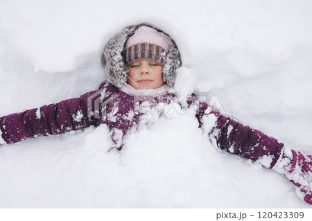 Adorable little girl bundled up in winter clothes, playing in a snowy wonderland. She stands joyfully among snow-covered trees, capturing the magic of a snowy day. 120423309