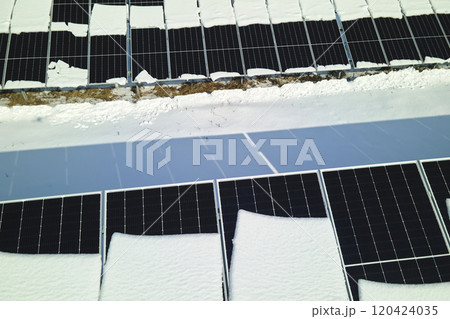 Aerial view of electrical power plant with solar panels covered with snow melting down in winter end for producing clean energy. Concept of low effectivity of renewable electricity in northern region 120424035