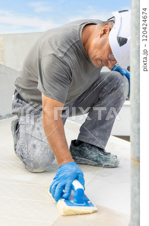 Craftsman in grey work clothes washing surface with a float during construction Craftsman in grey work clothes washing surface with a float during construction 120424674