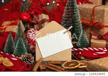White postcard and craft envelope near Christmas decor, trees, spices and red sweater, mockup 120424695