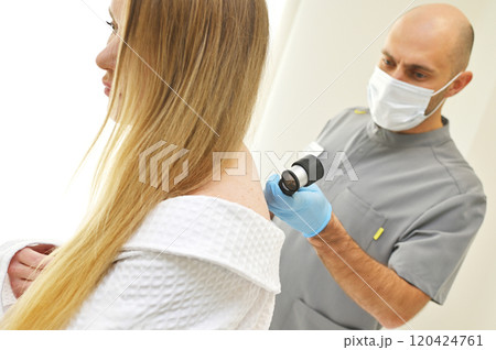 A dermatologist examines neoplasms on the patient's skin using a special dermatoscope device. Prevention of melanoma. A dermatologist examines neoplasms on the patient's skin using a special dermatoscope device. Prevention of melanoma. 120424761
