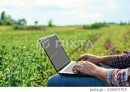 Farmer working with laptop in cultivated agricultural field 120425703