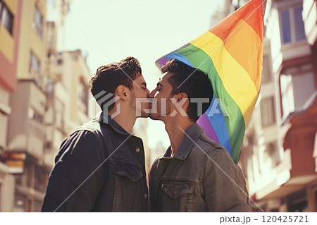 Gay couple kissing under rainbow flag, celebrating love and pride 120425721