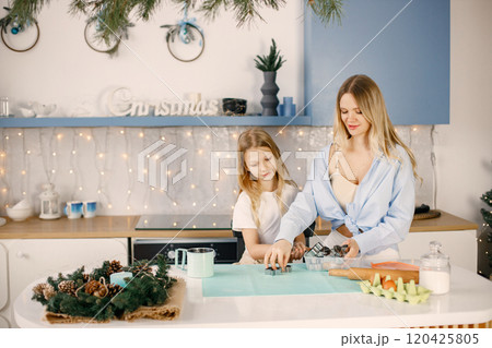 Family preparation of ginger biscuits with daughter. Mother and little girl cooking cookies. Blonde woman wearing blue shirt and girl white t-shirt. 120425805