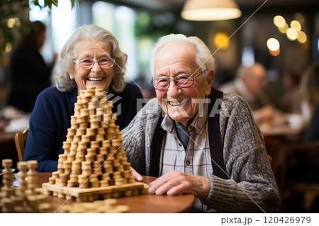 A man and a woman in a nursing home are playing a board game. 120426979