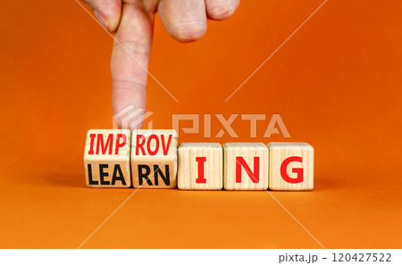Improving or learning symbol. Businessman turns wooden cubes and changes the word Improving to Learning . Beautiful orange background. Educational business improving or learning concept. Copy space. 120427522