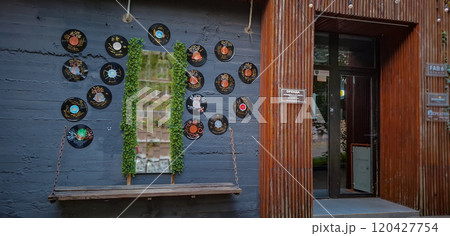 Photo zone near the entrance to the building. Vinyl records with mirrors and a hanging bench on a chain hang on the concrete wall. 120427754