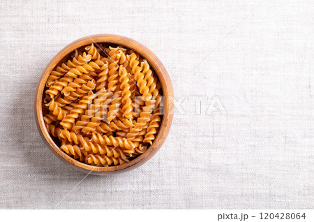 Chickpea spiral pasta in a wooden bowl, with empty space for text. Small fusilli, a pasta variety with helical or corkscrew shape, made of gluten free chickpea flour, an alternative to wheat flour. Chickpea spiral pasta in a wooden bowl, with empty space for text. Small fusilli, a pasta variety with helical or corkscrew shape, made of gluten free chickpea flour, an alternative to wheat flour. 120428064