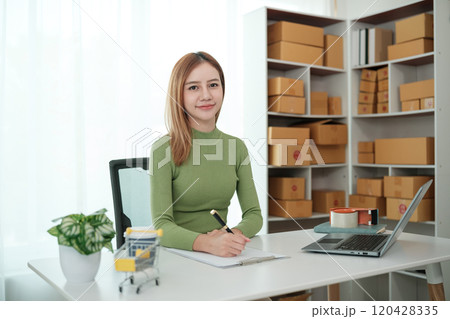 A woman is sitting at a desk with a laptop and a notebook A woman is sitting at a desk with a laptop and a notebook 120428335