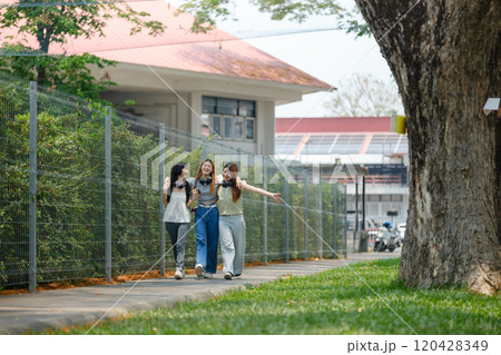 Three women walking down a sidewalk in front of a building Three women walking down a sidewalk in front of a building 120428349