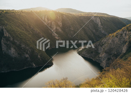 Stunning sunset over a serene river valley surrounded by rugged cliffs in the mountains of early spring in Serbia Stunning sunset over a serene river valley surrounded by rugged cliffs in the mountains of early spring in Serbia 120428426