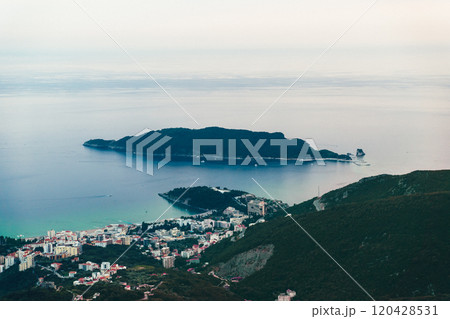 Aerial view of the coastline with a distant island and serene waters at dawn, showcasing natural beauty and tranquility 120428531