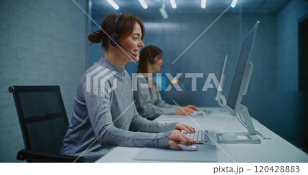 Female helpdesk specialist talking on headset with customer, working on computer 120428883