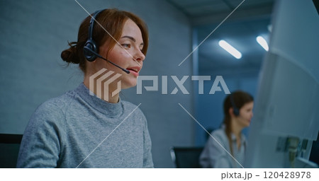 Positive female helpdesk specialist talking on headset, providing online assistance Positive female helpdesk specialist talking on headset, providing online assistance 120428978