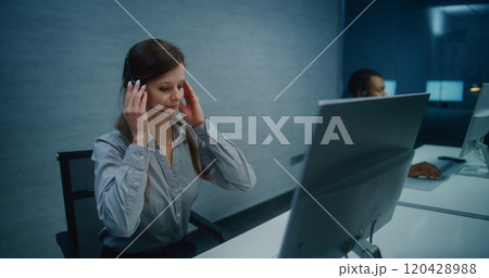 Female hotline operator wears headset, starts night shift providing online customer service Female hotline operator wears headset, starts night shift providing online customer service 120428988