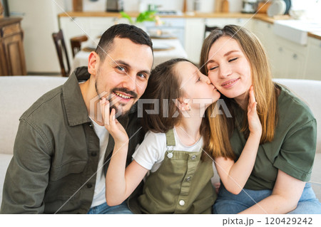 Happy family at home. Mother father children daughter relaxing on sofa indoor. Mom dad parents kid girl relax playing hugging having fun together. Family smiling laughing enjoying tender moment 120429242