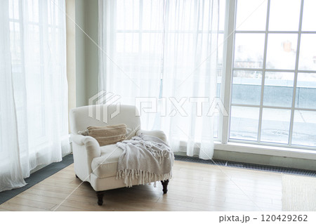 Stylish loft interior. Spacious design apartment with light walls large windows white armchair. Clean modern decoration with elegant furniture in minimalist Scandinavian style Stylish loft interior. Spacious design apartment with light walls large windows white armchair. Clean modern decoration with elegant furniture in minimalist Scandinavian style 120429262
