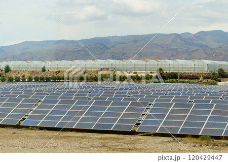 Solar panels of the power plant against the backdrop of greenhouses and mountains. Solar panels of the power plant against the backdrop of greenhouses and mountains. 120429447