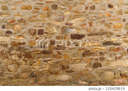The texture of the old medieval wall of the house, lined with brown stone 120429614