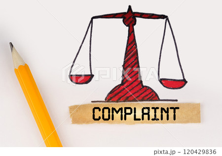 Next to the painted scales of justice lies a pencil and a strip of paper with the inscription - Complaint 120429836
