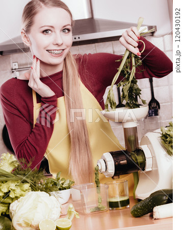 Woman in kitchen making vegetable smoothie juice 120430192