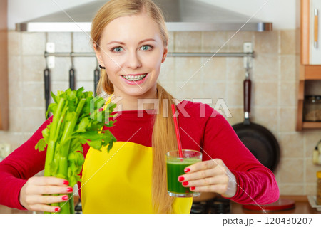 Woman in kitchen holding vegetable smoothie juice Woman in kitchen holding vegetable smoothie juice 120430207