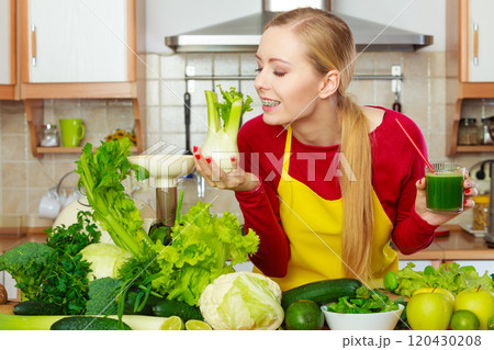 Woman in kitchen holding vegetable fennel smoothie juice Woman in kitchen holding vegetable fennel smoothie juice 120430208