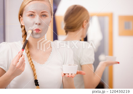 Woman applying with brush clay mud mask to her face 120430219