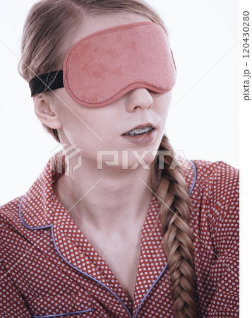Sleepy woman wearing pink eye band 120430280