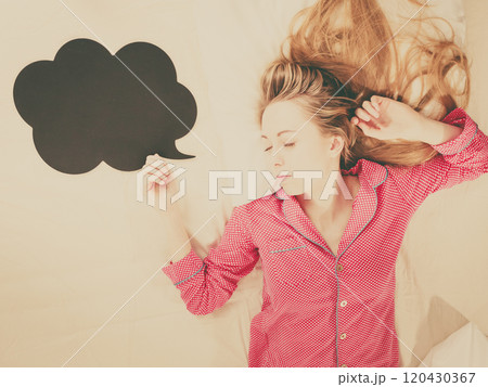 Young woman lying on bed wearing pajamas Young woman lying on bed wearing pajamas 120430367