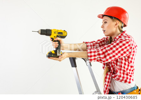 Woman using drill on ladder Woman using drill on ladder 120430685