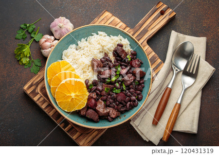Feijoada, traditional brazilian stew with black beans, rice, and orange slices, in plate on rustic table top view 120431319