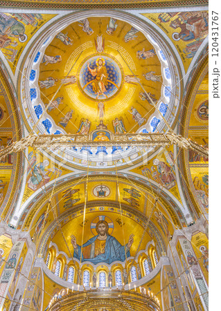 The intricate dome of the Church of Saint Sava showcases stunning gold and colorful murals, depicting religious figures in a captivating blend of artistry and spirituality. 120431767