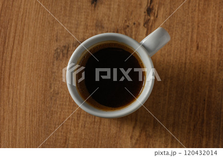 A warm cup of black coffee resting on a rustic wooden table during a peaceful morning moment 120432014