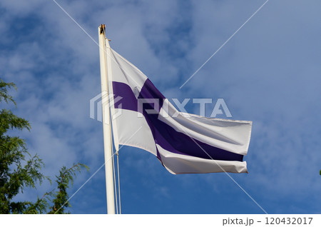 Finnish flag waving proudly against a bright blue sky, embraced by nature on a sunny day 120432017
