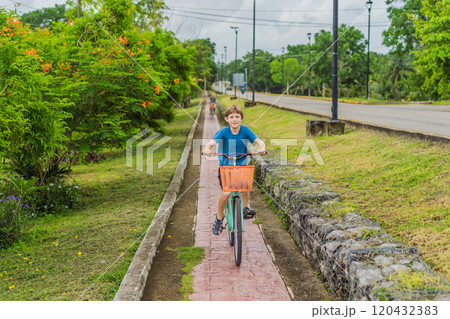 Boy tourist cycling through the charming village of Bacalar, Mexico. Quintana Roo travel, scenic bike paths, and eco-friendly exploration concept 120432383