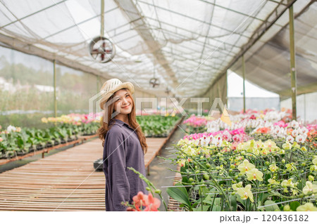 A Beautiful Woman in a Floral Greenhouse is Surrounded by Colorful, Vibrant Blooms 120436182