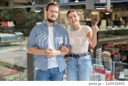 Couple looking for something in furniture store, searching for perfect item to complete living space Couple looking for something in furniture store, searching for perfect item to complete living space 120438405