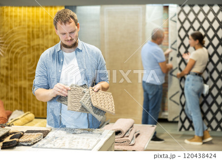Young man choosing carpet samples in store 120438424