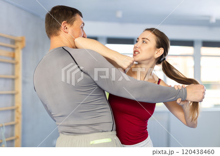 Self-defense training - woman practicing blows to the head of male attacker 120438460