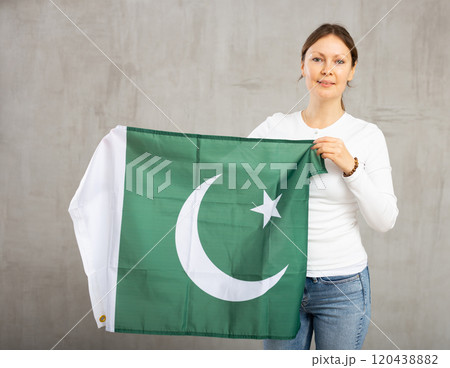 Smiling woman waving flag of Pakistan against gray background 120438882