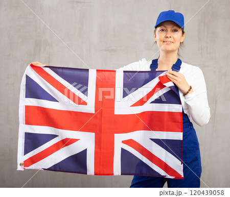 Smiling adult woman in uniform holding UK flag 120439058