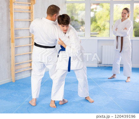 Male athletes in pair conduct training battle in oriental fighting technique under guidance of coach Male athletes in pair conduct training battle in oriental fighting technique under guidance of coach 120439196