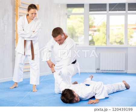 Male athletes in pair conduct training battle in oriental fighting technique under guidance of coach 120439199