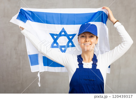 Cheerful female worker with wide grin on her face holding flag of israel Cheerful female worker with wide grin on her face holding flag of israel 120439317