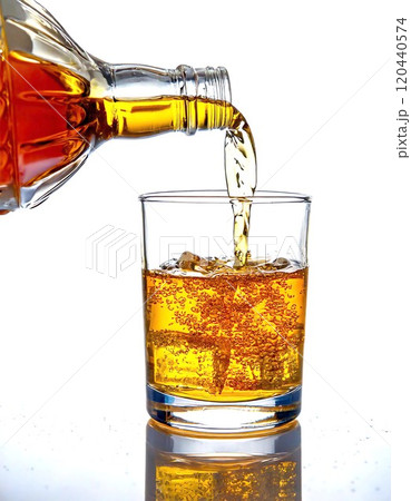 A refreshing beverage being poured into a glass filled with ice cubes. 120440574
