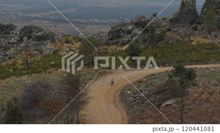 Mountain biker on a winding path in fire-scorched landscape 120441081